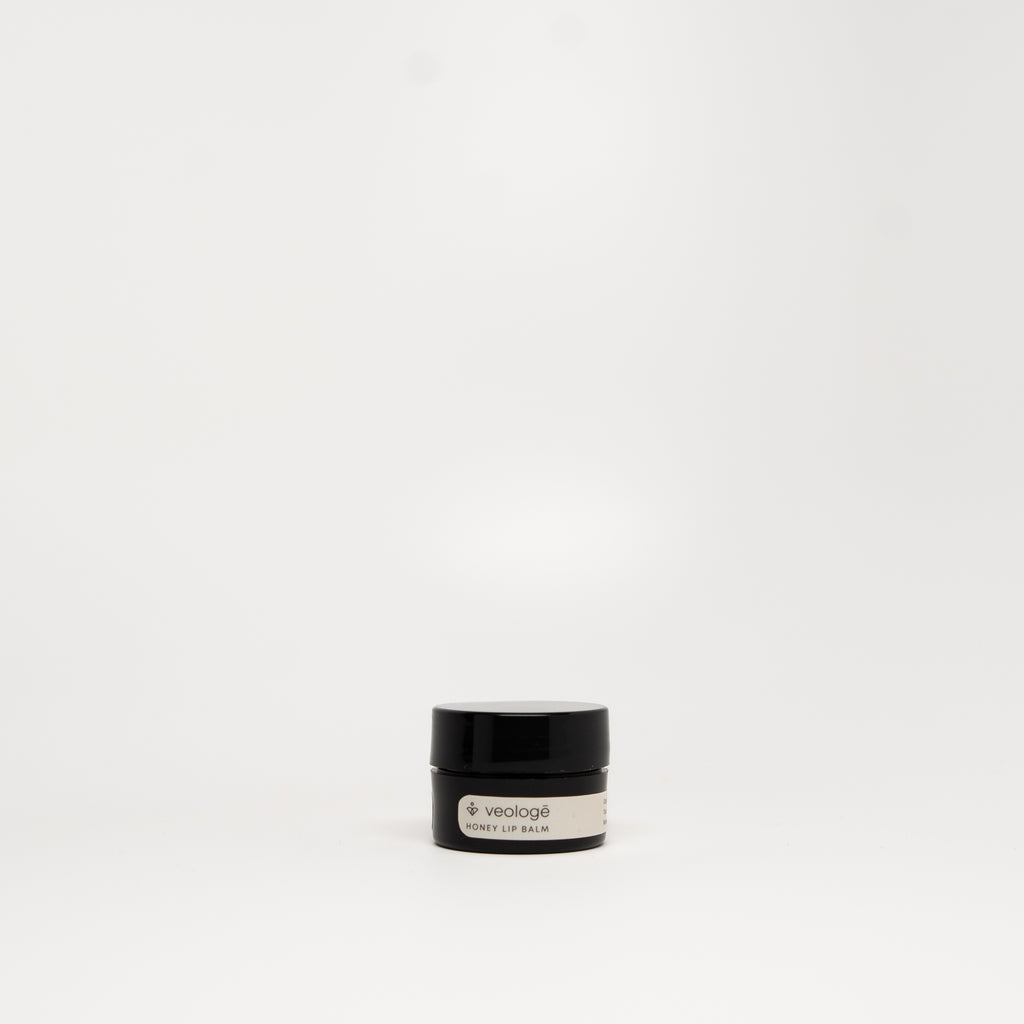 veologē Honey Lip Balm, ten-ingredient natural balm with real honey, shea butter, and rosehip oil for lips, cuticles, and eye area.